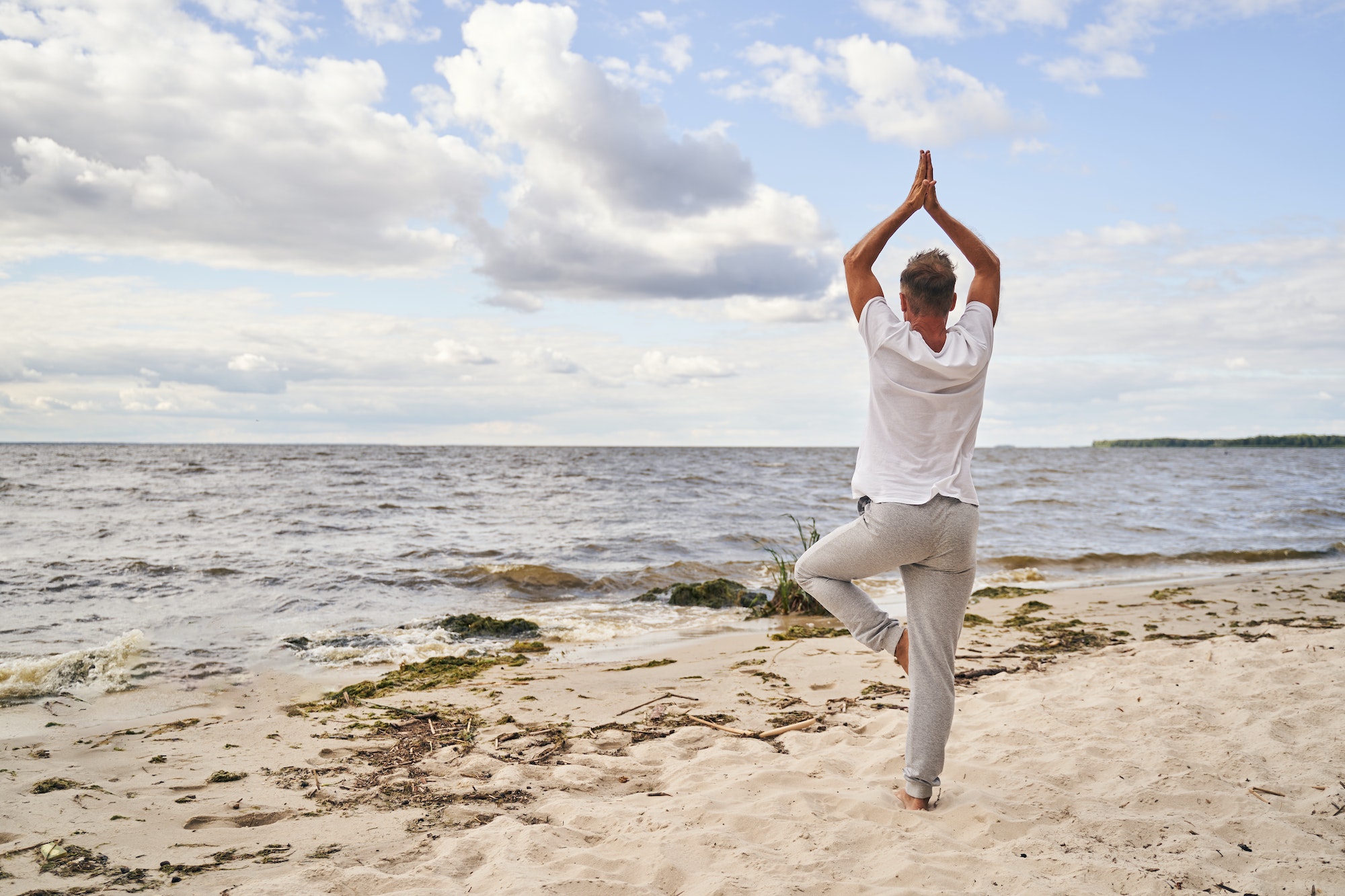 Man practicing yoga in solitude in beach