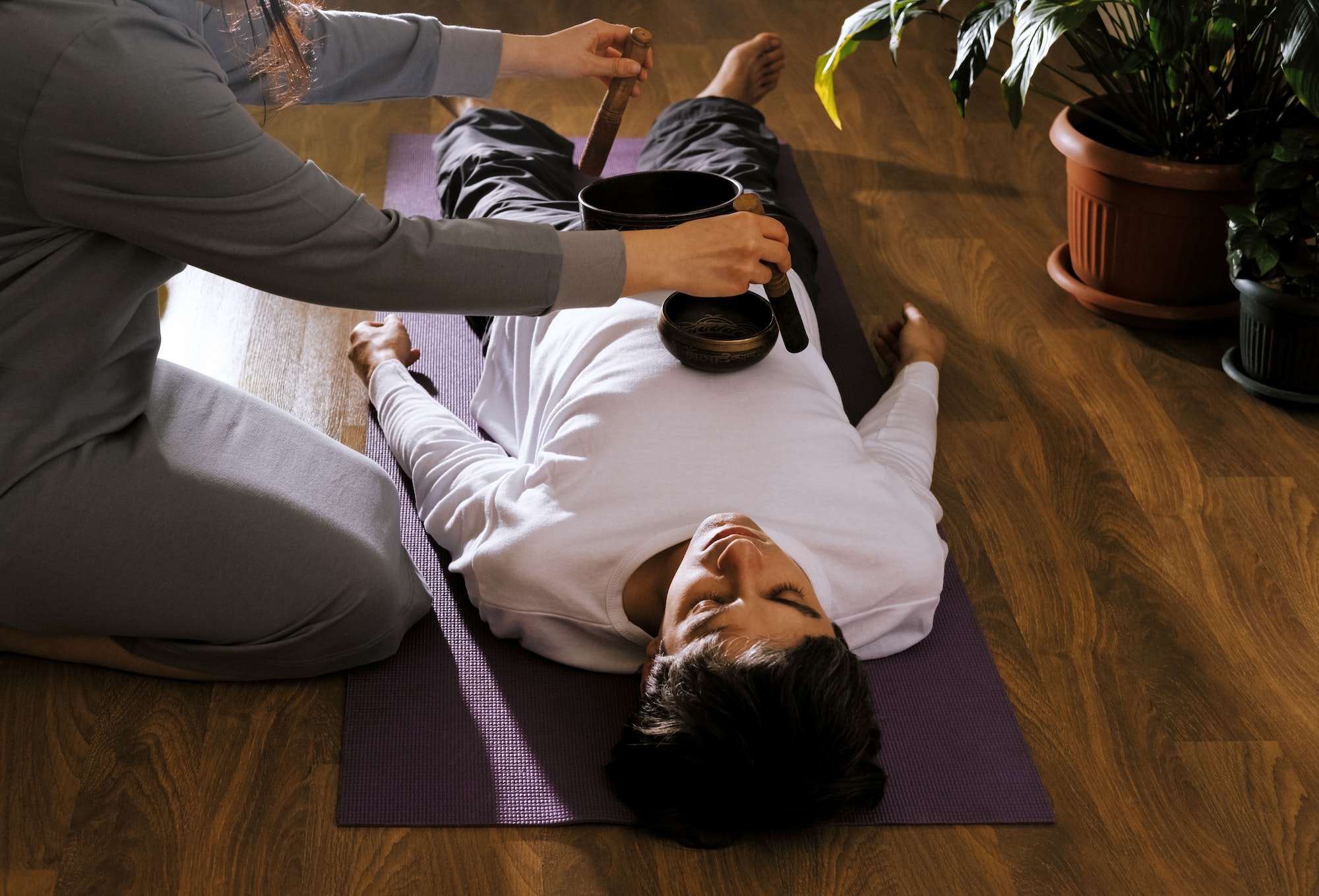 Woman making relaxing massage for young man. Meditation, sound therapy with Tibetan singing bowls.